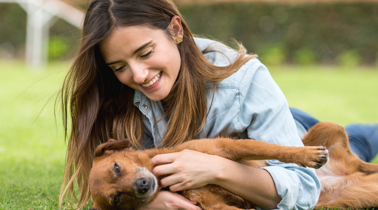 Lady cuddling dog on grass